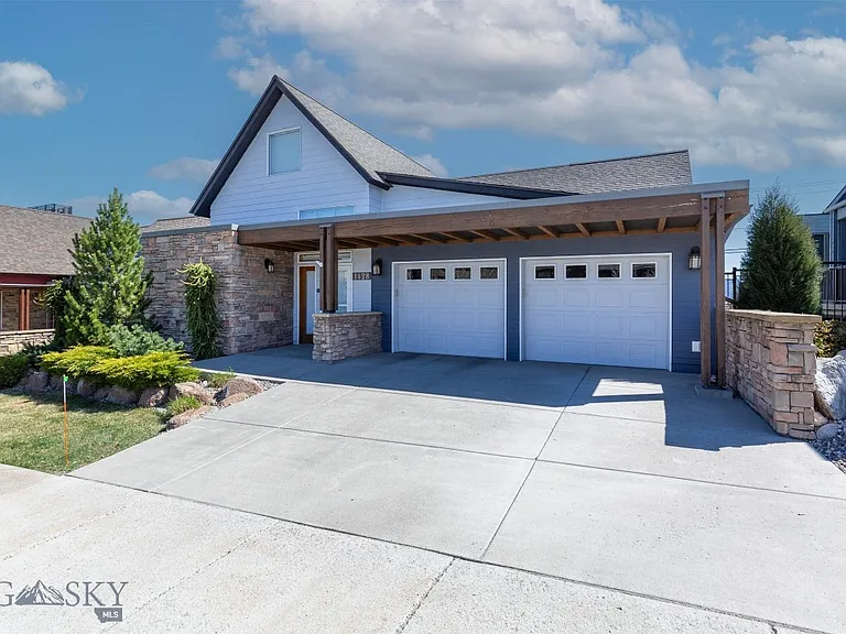Residential home with two white sectional garage doors and stone accents